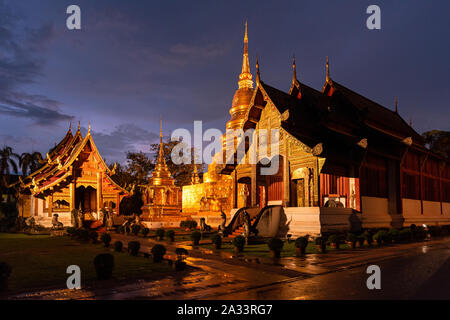 Temple Phra Singha pagode d'or lumière après la pluie dans crépuscule du soir. Banque D'Images