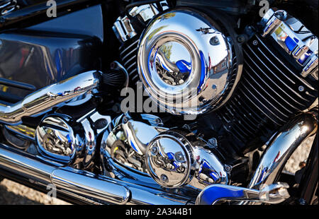 Partie d'un moteur de moto, un classique américain avec beaucoup de chrome et réflexions d'autres motos à proximité Banque D'Images
