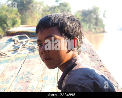 Mauvais Garçon cambodgiennes travaillant sur un bateau dans le village flottant Banque D'Images