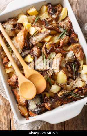 Fricassée de poulet suisse avec des champignons sauvages et pommes de close-up dans un plat allant au four, sur la table. Haut Vertical Vue de dessus Banque D'Images