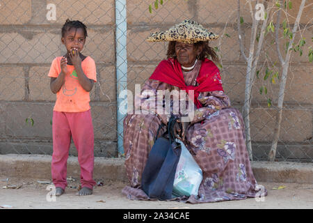 Omatjete, Namibie - 24 juillet 2019 : personnes âgées Femme Herero en costume traditionnel assis et debout, fille noire montrant effectuer de traditionnelles et modernes Banque D'Images