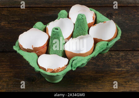 Studio shot de craquage, coquilles d'œufs de poulet vide dans une boîte sur un fond de bois foncé - John Gollop Banque D'Images