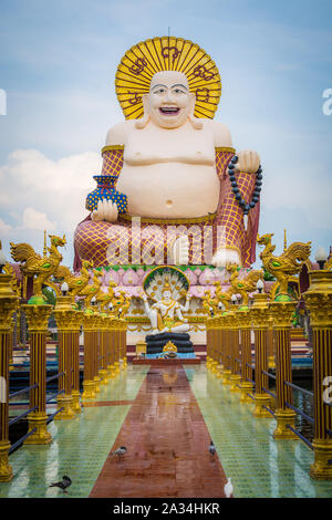 Sourire géant ou Happy Buddha statue avec ciel bleu en temple bouddhiste ( wat Plai Laem ), Koh Samui, Thaïlande. Banque D'Images