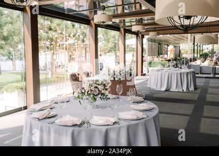 Le banquet de mariage dans un hall élégant avec des fenêtres panoramiques à l'étage. Belle la floristique et élégamment décorée, l'époux et épouse le tableau Banque D'Images
