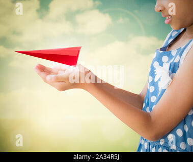 Petite fille en prenant soin et en maintenant l'avion origami papier rouge avec fond nature Banque D'Images