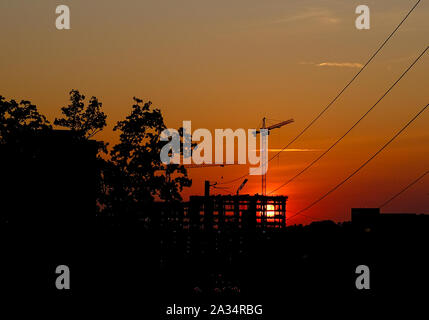 Lever du soleil qui brillait à travers un nouveau bâtiment sur un chantier avec des grues Banque D'Images