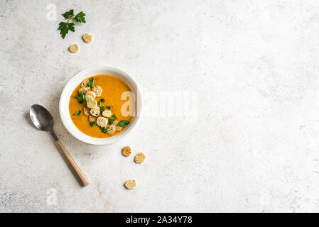 Soupe de légumes garnie de croûtons et le persil dans un bol sur fond blanc, vue du dessus, copiez l'espace. Régime alimentaire végétarien saisonnière saine - si fait maison Banque D'Images
