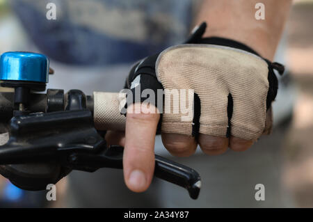 Close-up of a man's main gantée sur le guidon d'un vélo de montagne Banque D'Images
