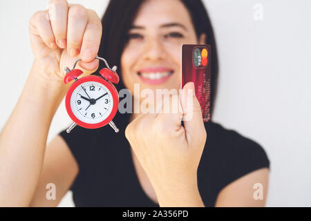 Payer par carte de crédit. femme hands holding credit card et du réveil. Les achats en ligne. Concept d'achat en ligne . Carte de crédit et réveil sur le livre blanc Banque D'Images