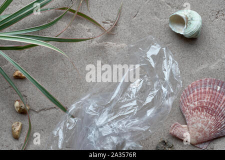 Sac en plastique transparent à usage unique sur une plage de sable. La pollution plastique est nuisible à la vie marine. Interdire l'utilisation unique de la campagne en plastique. Shallow DOF, focu Banque D'Images