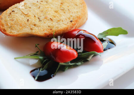 Garnir de tomates cerises avec du vinaigre balsamique et du pain à l'ail Banque D'Images