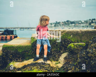 Un petit enfant est assis dans le port un jour d'été Banque D'Images