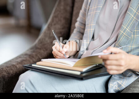 Mains de jeune femme élégante avec un crayon sur la page de cahier Banque D'Images