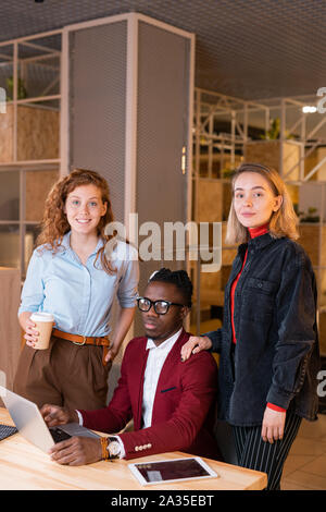 Les jeunes hommes assis entre deux collègues femmes caucasiennes Banque D'Images