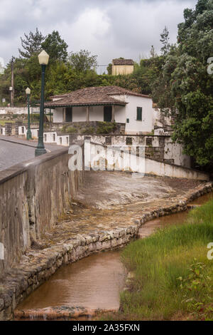 Rivière de l'hot Sulphur Springs, entre une route et une forêt. Bâtiment en arrière-plan. Domaine de la célèbre spa. Furnas, Sao Miguel, Açores, Banque D'Images