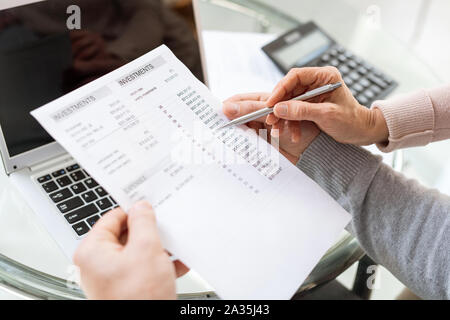 Male hands holding document financier tandis que sa femme pointant sur somme d'argent Banque D'Images