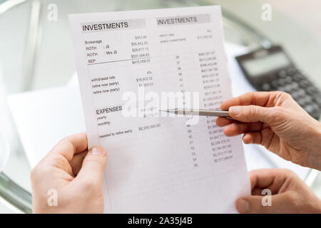 Human hand holding pen en pointant sur somme d'argent dans le document financier Banque D'Images