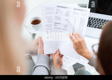 Main de conseiller financier avec stylo pointant vers le document en somme à Banque D'Images