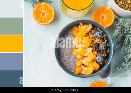 Chia pudding avec mandarine et thé matcha dans un bol de granola sur fond de bois turquoise pastel. Échantillon de couleur Banque D'Images