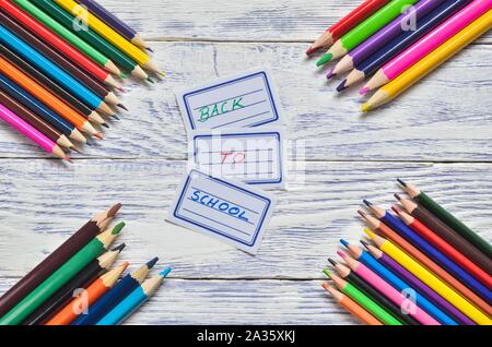 Concept créatif avec les fournitures scolaires. Les étiquettes avec texte retour à l'école et des crayons sur un bureau en bois. Banque D'Images