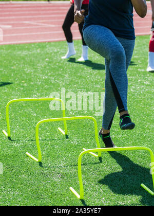 Un coureur est d'effectuer des exercices d'yovr mini jaune vitesse obstacles banane avec pas de chaussures sur la piste et sur le terrain au cours de la pratique. Banque D'Images