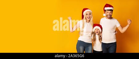 Les parents et la fille à Santa Hats Shaking Fists dans Studio, Panorama Banque D'Images