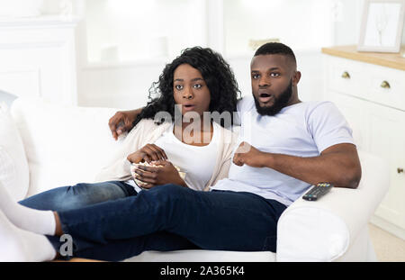 Contenu de choc. Surpris african american couple watching tv show ensemble Banque D'Images