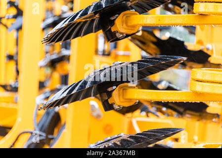 Détail de la machine de l'agriculture dans les temps difficiles. Close up de parties en acier, tubes, engrenages, roues, pneus, Système hydraulique avec la pluie. Banque D'Images