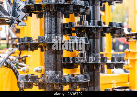 Détail de la machine de l'agriculture dans les temps difficiles. Close up de parties en acier, tubes, engrenages, roues, pneus, Système hydraulique avec la pluie. Banque D'Images