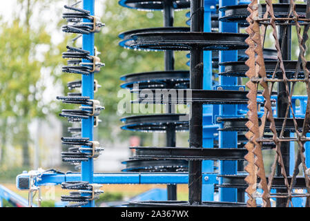 Détail de la machine de l'agriculture dans les temps difficiles. Close up de parties en acier, tubes, engrenages, roues, pneus, Système hydraulique avec la pluie. Banque D'Images