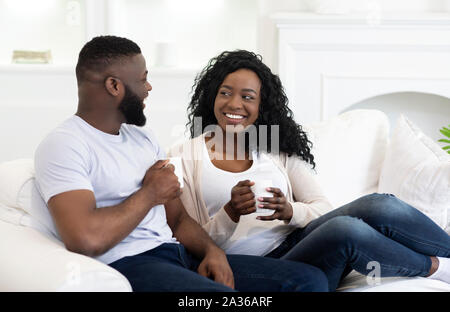 Happy black couple relaxing on couch et boire du café Banque D'Images