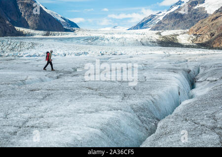 Profondément dans la chaîne de montagnes de la frontière entre l'Alaska et le Canada, un grimpeur sur glace marche à travers l'énorme Glacier Salmon. Banque D'Images