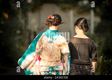 Femme portant un kimono japonais accompagné d'une autre femme en robe noire. Banque D'Images