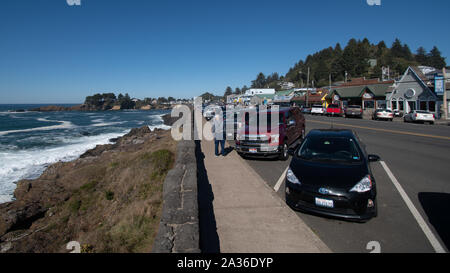 Depoe Bay, Oregon - 13 octobre 2019 : des voitures garées le long du littoral, avec des magasins de l'autre côté de la Route 101 l'autoroute. Banque D'Images