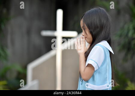 La minorité de l'enfant fille priant et Cross Banque D'Images