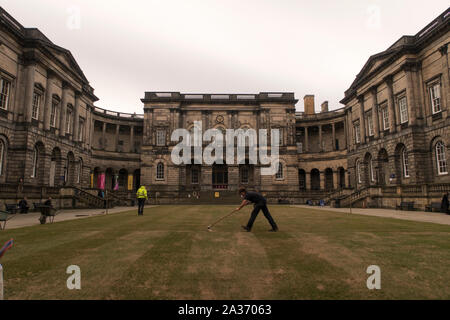 Un homme balayant l'herbe à l'Université d'Édimbourg Quadrangle Banque D'Images