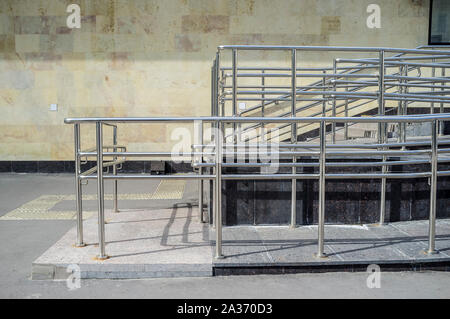 Garde-corps, rampe avec plan incliné pour fauteuils roulants et les chariots installé à côté des escaliers pour les mouvements. Banque D'Images