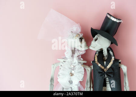 Les squelettes dans la robe de mariage mariée marié sur le fond rose pale. Banque D'Images