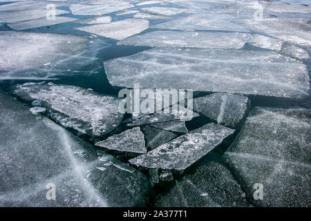 La texture de l'hiver avec des morceaux de glace flottant sur l'eau. La glace fissurée scintille au soleil. Grands et petits morceaux. Banque D'Images