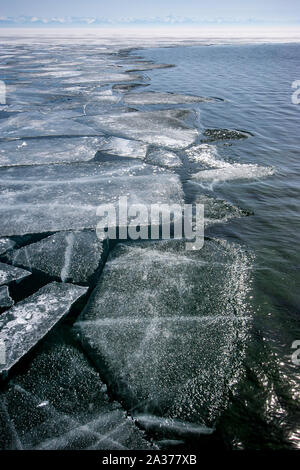 Lac Baikal en hiver avec de l'eau libre et le bord de la glace brisée. Une chaîne de montagnes à l'horizon. Orientacion verticale. Banque D'Images