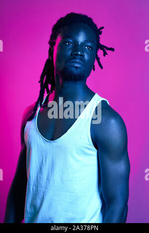 Triste Malheureux homme musclé à la grave à la distance, guy avec une peau sombre sain, violet background, studio shot Banque D'Images