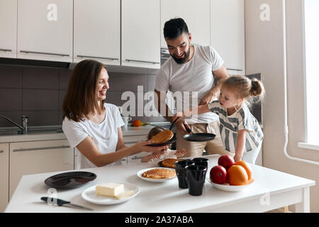 Girl putting laborieux , le déplacement des crêpes sur la plaque, la photo en gros. meilleur assistant. la photo en gros, tradition familiale Banque D'Images