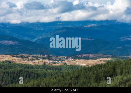 Village bulgare en Konarsko Rhodopes en face de montagne de Rila au cours de journée d'automne nuageux Banque D'Images