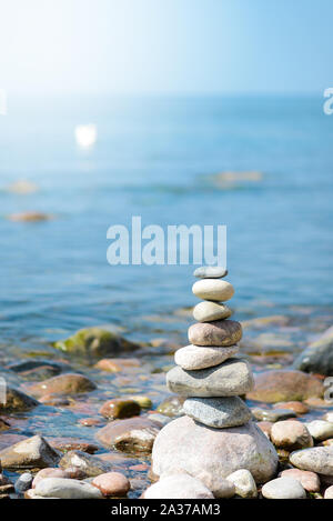 Pyramide de galets dans la journée ensoleillée.Sur le bord de la mer une pyramide de pierres. Rêve sur la plage. Banque D'Images