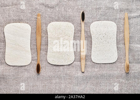 Brosses à dents en bois naturel et washclothers sur fond gris, vue du dessus Banque D'Images