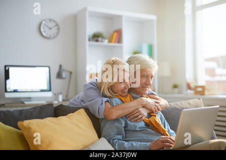 Portrait de senior tout en travaillant à la maison avec femme aimante l'enlaçant, copy space Banque D'Images