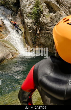 Touristes en combinaisons de protection et casques canyoning les Cascades de Purcaraccia, Quenza, Corse Bavella montagnes - Corse vacances aventure Banque D'Images