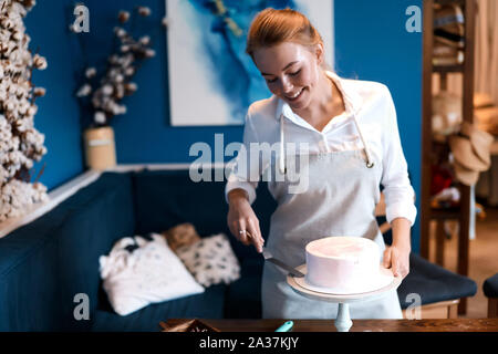 Smiling confiseur en compagnie de ses travaux dans la cuisine moderne salle. la photo en gros Banque D'Images