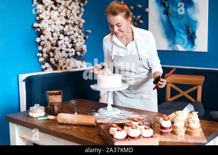 Smiling cook noix de pin mise sur le gâteau dans la cuisine, la photo en gros, passe-temps, loisirs Banque D'Images