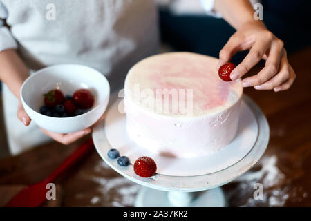 Confiseur decorating cake aux fruits rouges. Le concept de pâtisserie maison, gâteaux de cuisson.close up photo recadrée de vie. Banque D'Images